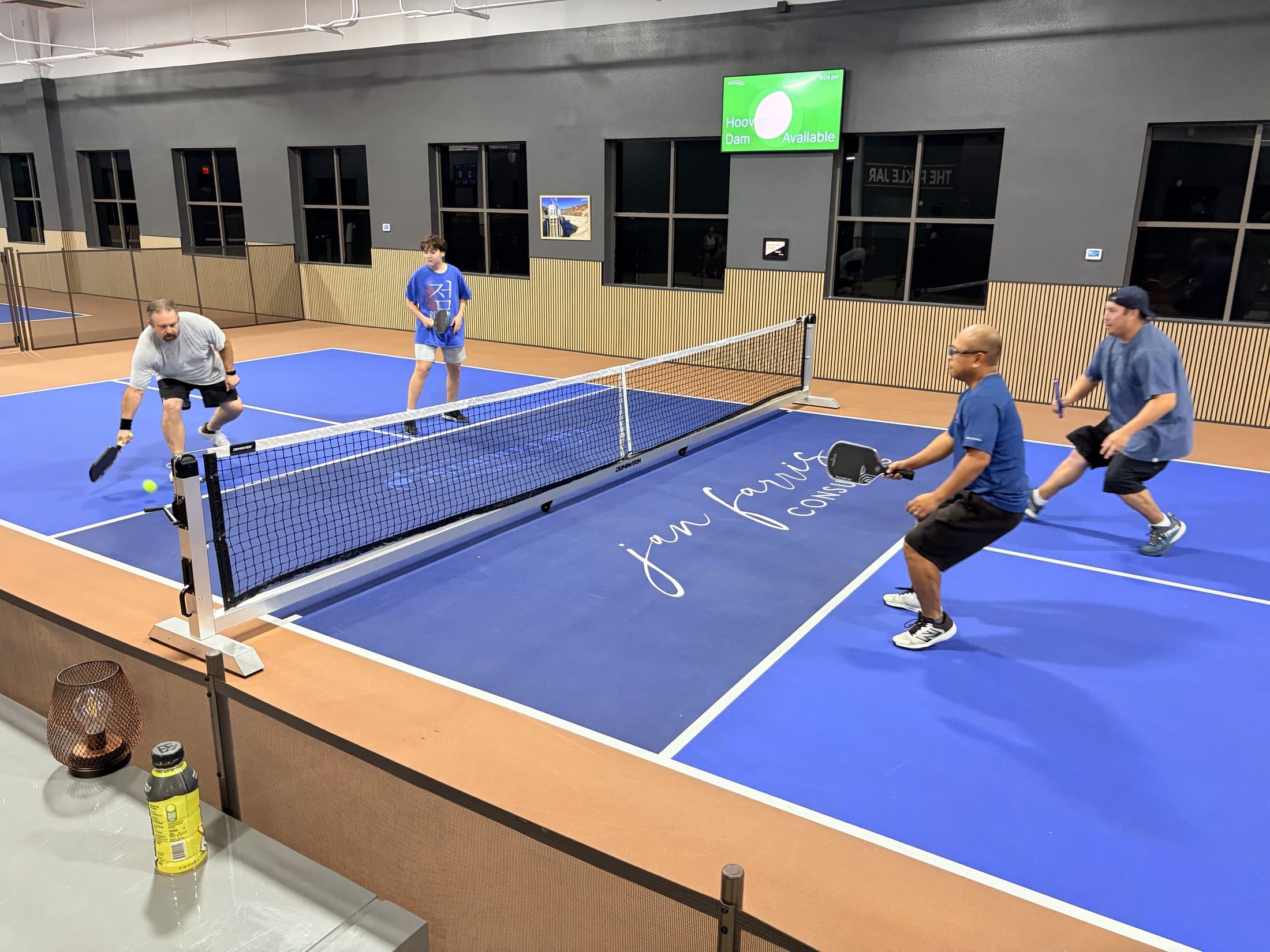 Competitive group pickleball game on a blue indoor court at The Courts LV