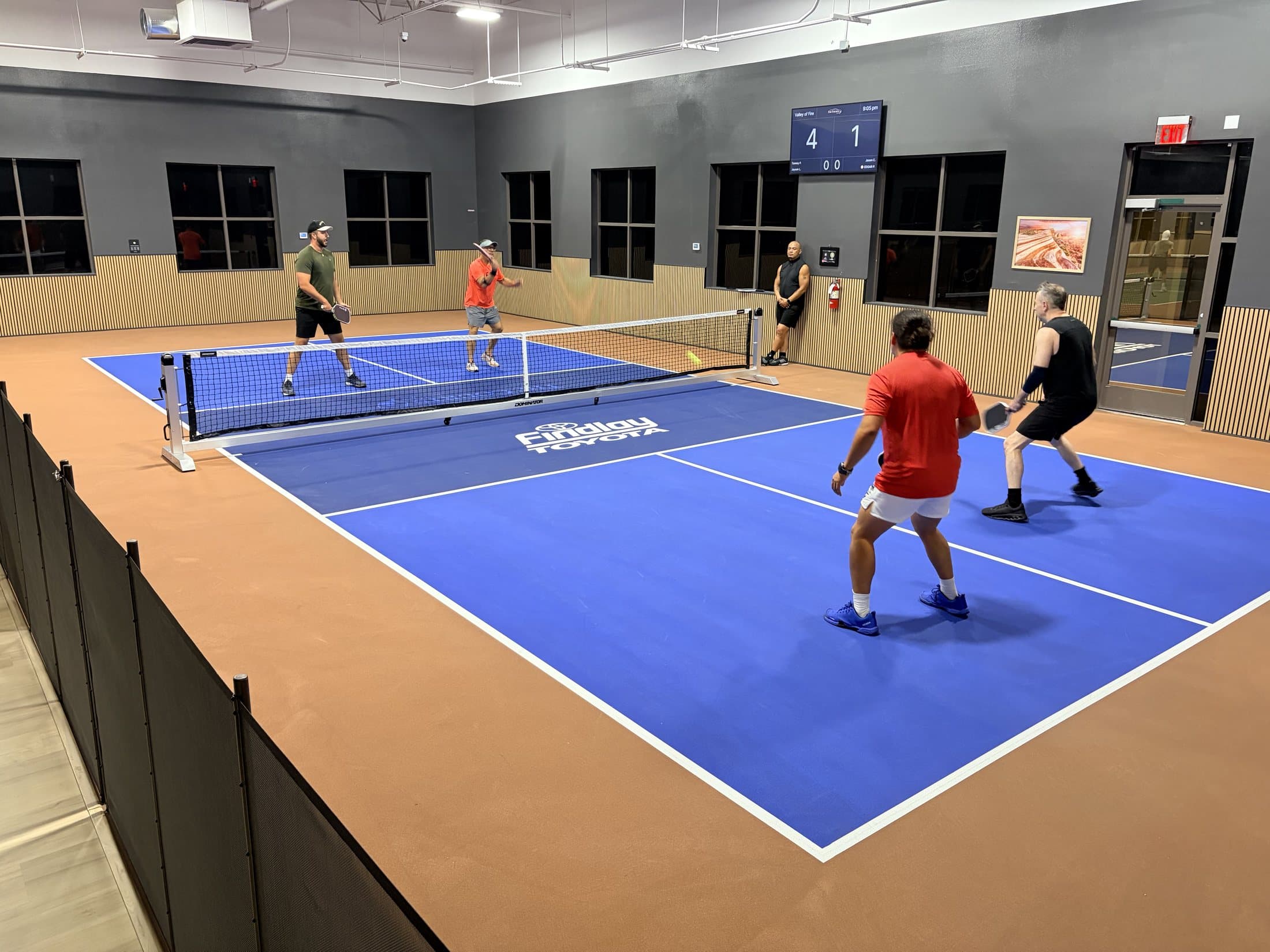 Blue indoor pickleball court rental with players at The Courts LV